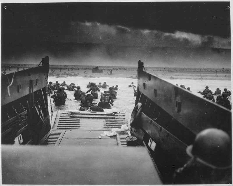 U.S. soldiers disembark from a landing craft under heavy fire off the coast of Normandy, France, June 6, 1944.