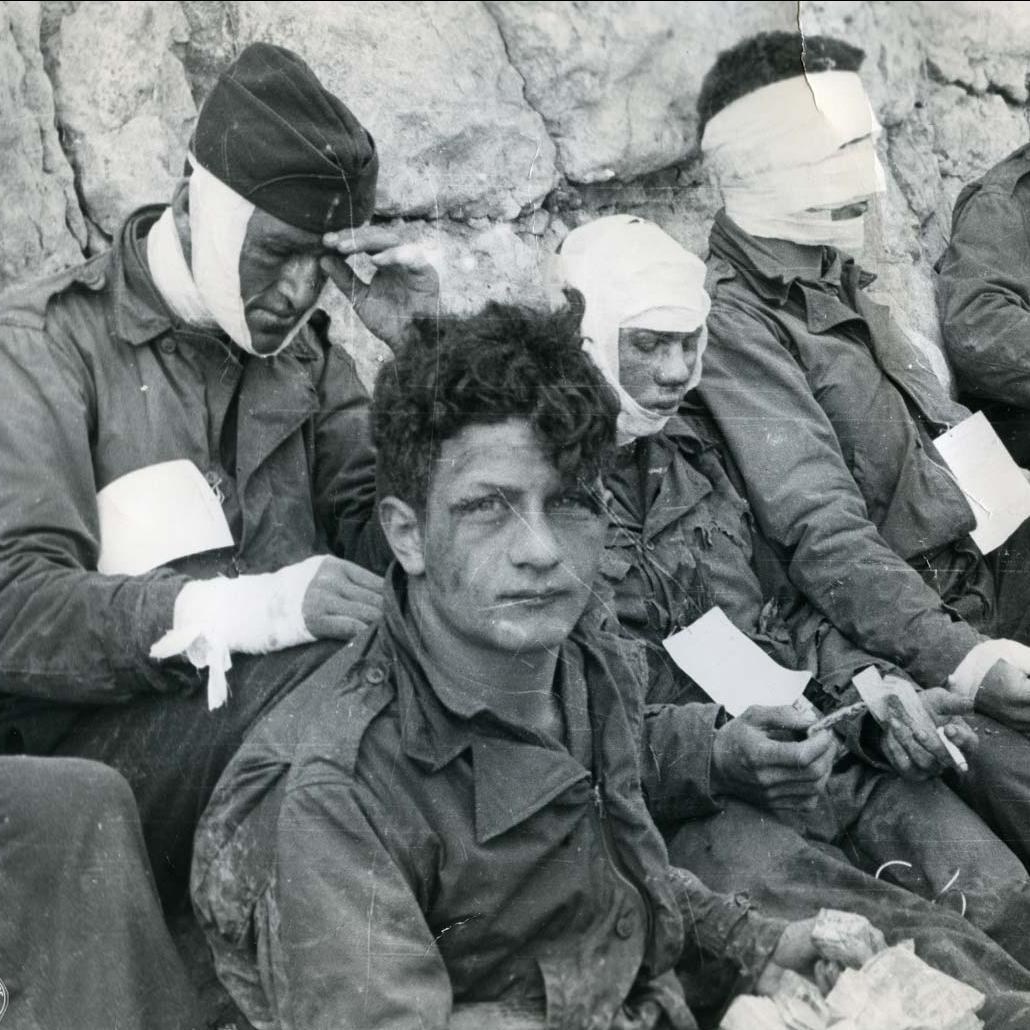 American assault troops of the 3rd battalion, 16th Infantry Regiment, 1st U.S. Infantry, injured while storming Omaha Beach, wait by the Chalk Cliffs for evacuation.
